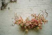 an arrangement of pink flowers on a white brick wall