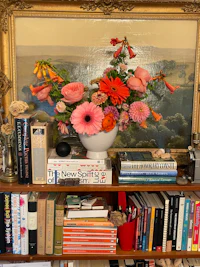a vase of flowers on a bookshelf