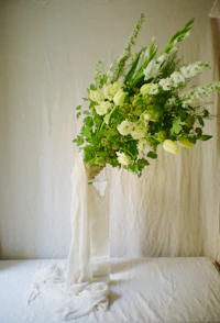 a bouquet of white flowers in a vase on a bed