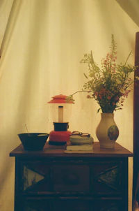 a table with a vase of flowers and a lamp